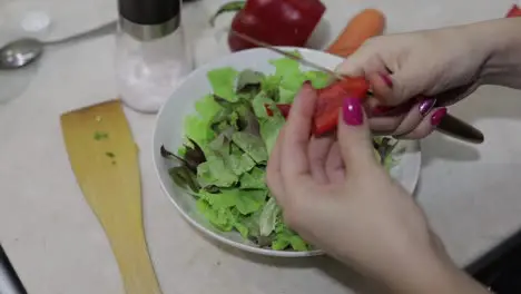 Female hands cut a sweet red bell Pepper to a salad