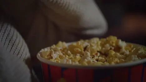 Female hand picking popcorn from paper bucket closeup Eating pop corn at cinema