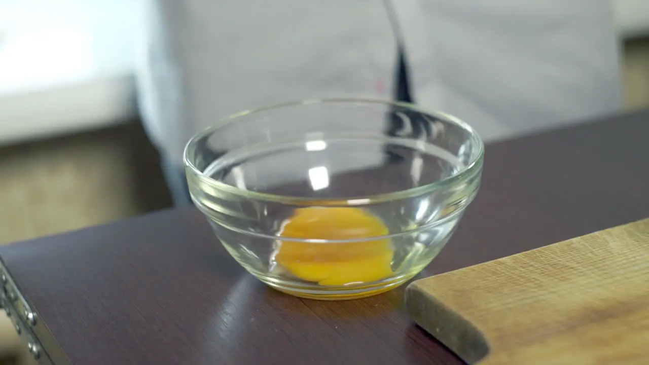 Egg yolk falling in glass bowl Food ingredient preparing ingredients for baking