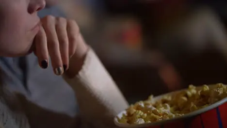 Girl taking popcorn from paper bucket to mouth Woman eating pop corn at cinema