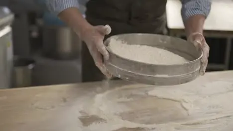 Hands holding sieve and sifting flour at the kithen Close up indoor slow motion