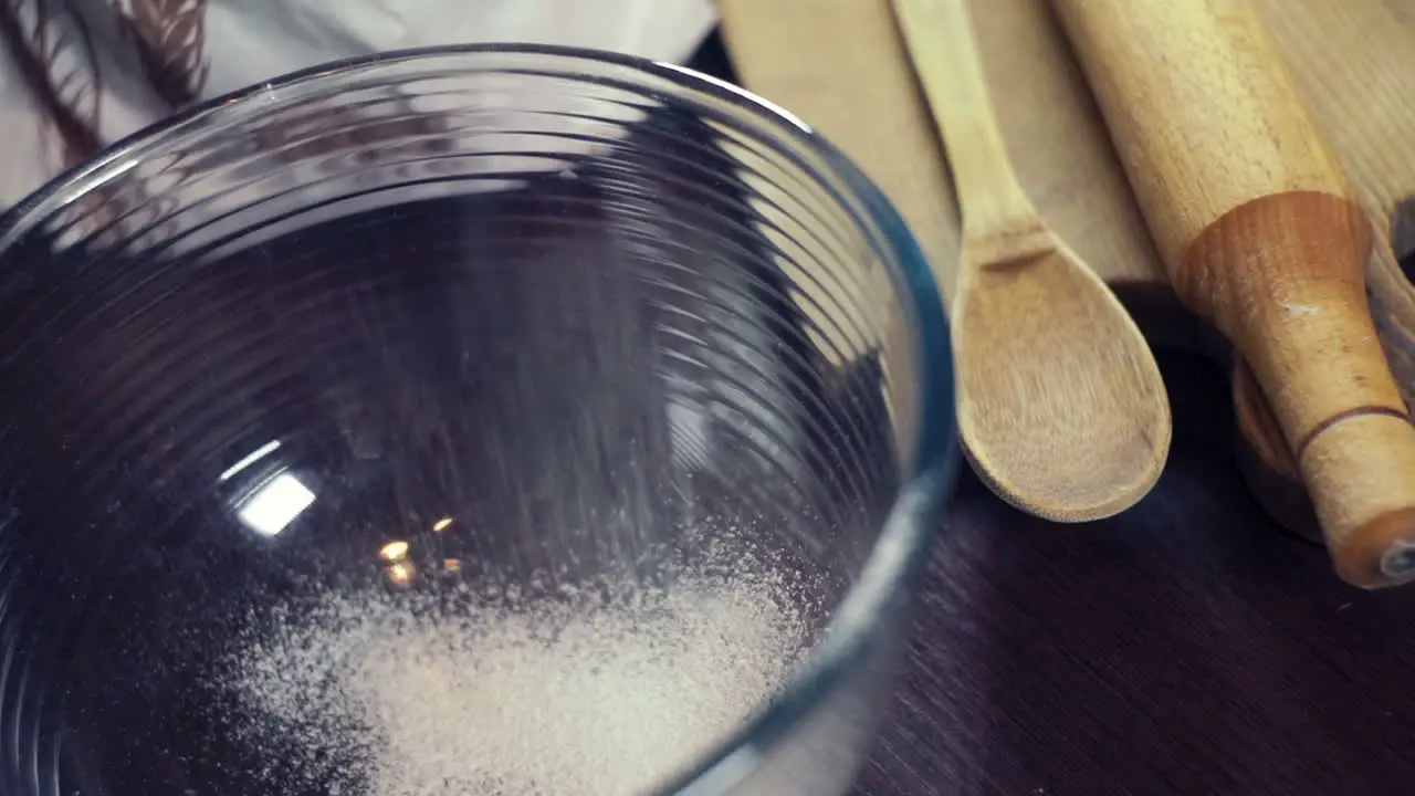 Powdered sugar for icing falling in a deep glass bowl