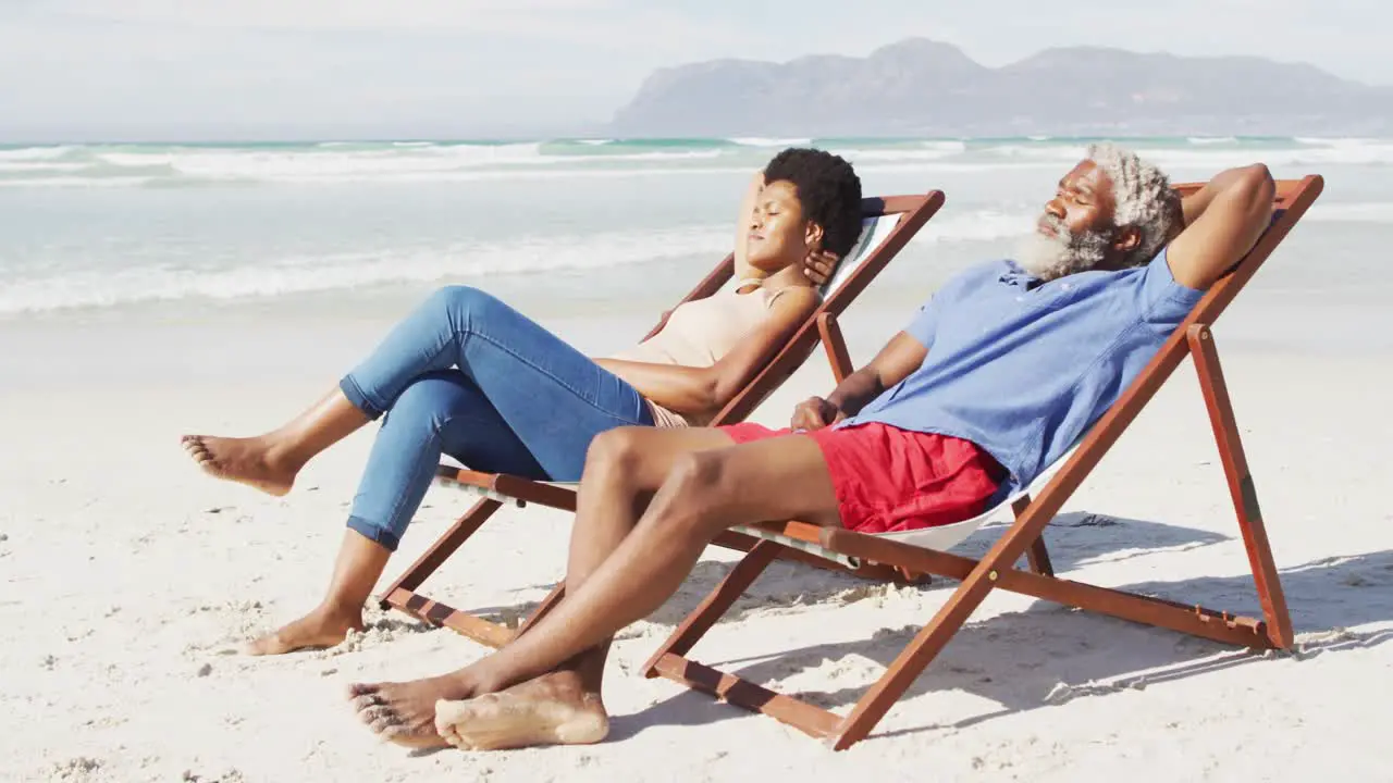 African american couple lying on sunbeds on sunny beach