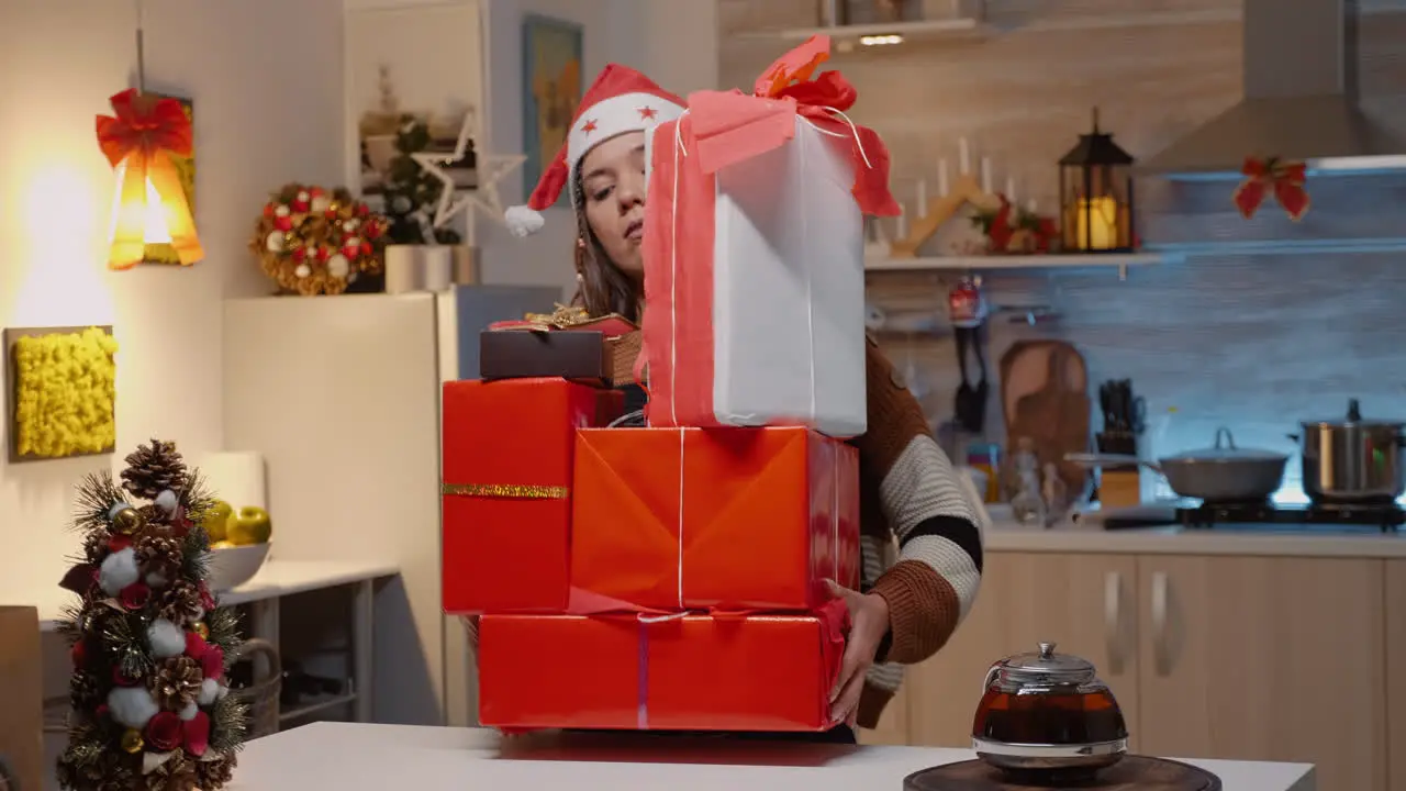 Festive woman bringing boxes of gifts on kitchen counter