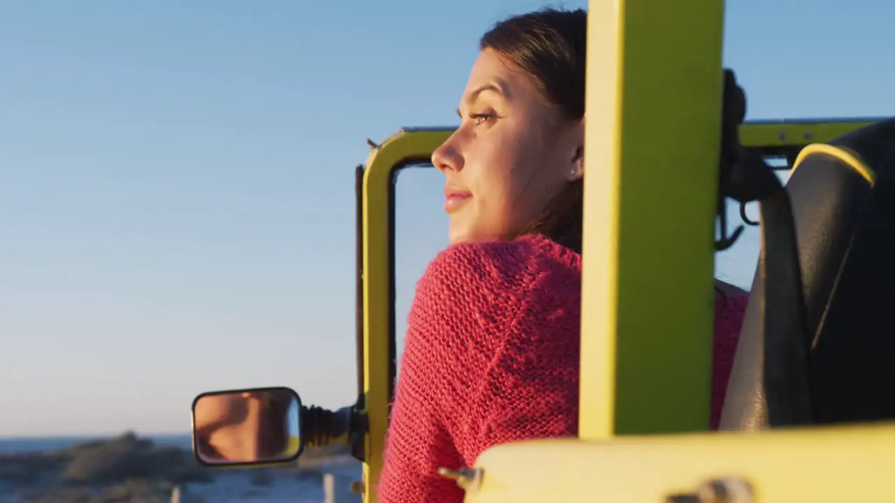 Happy caucasian woman sitting in beach buggy by the sea