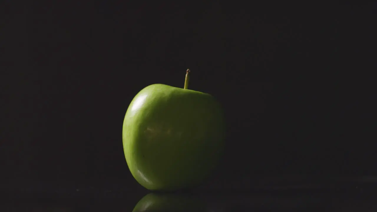 Studio Shot Of Green Apple Revolving Against Black Background