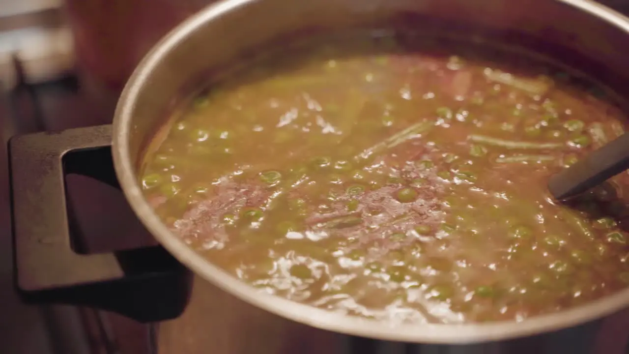 Boiling soup with ladle in the pot close up slow panning shot