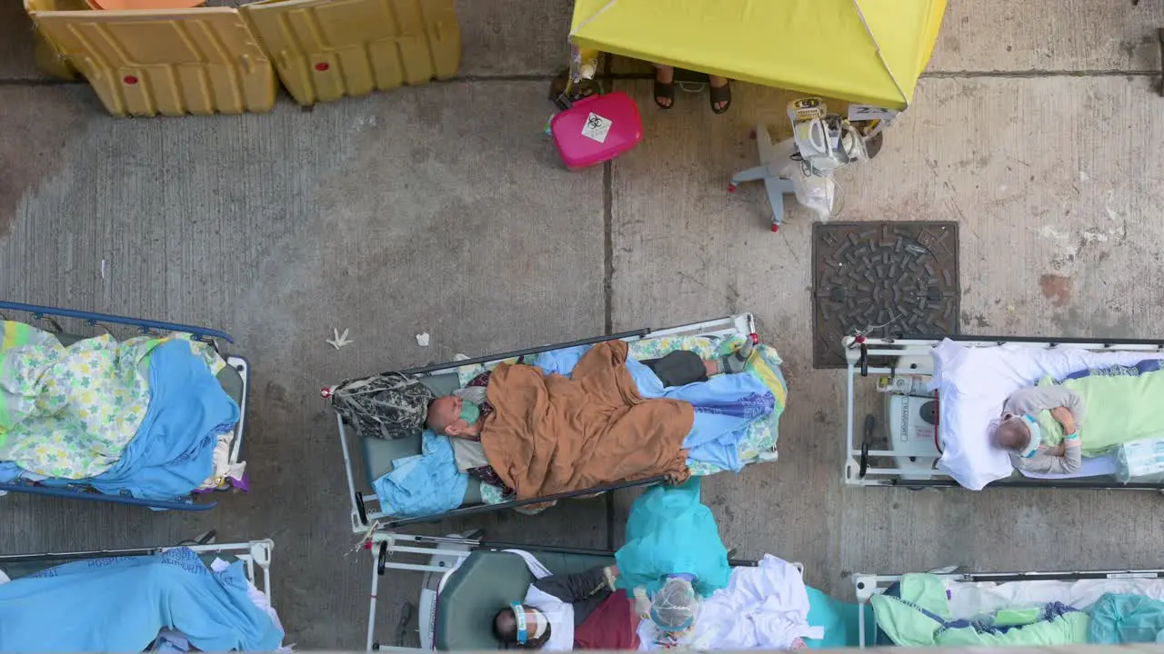 Healthcare workers attend to Chinese ill patients with Covid-19 symptoms lying in the bed outside an overcrowded hospital while the medical system collapses with hospitalizations