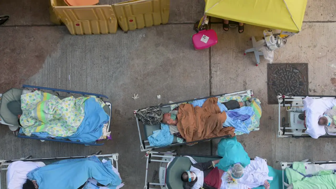 A healthcare worker attends to ill patients with Covid-19 symptoms lying in the bed outside an overcrowded hospital while the medical system collapses with hospitalizations