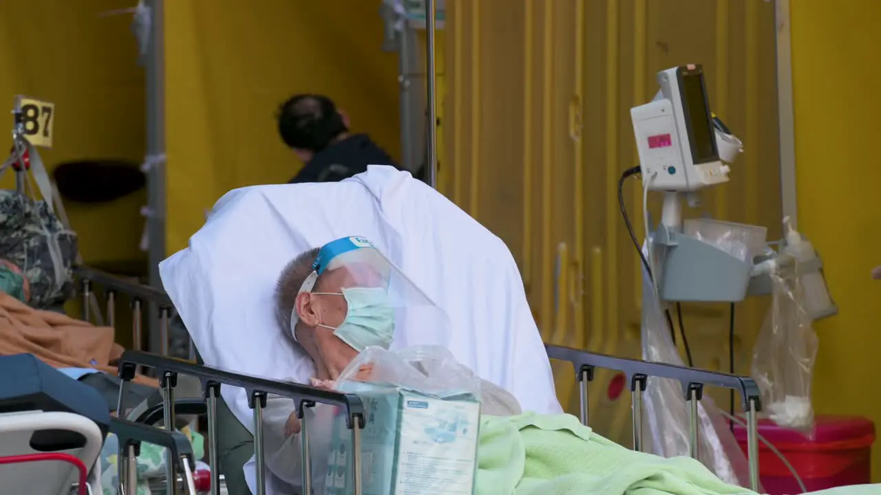 A patient with Covid-19 symptoms rests as he lies in bed outside an overcrowded hospital while the medical system collapses with hospitalizations