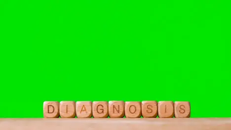 Medical Concept With Wooden Letter Cubes Or Dice Spelling Diagnosis Against Green Screen Background