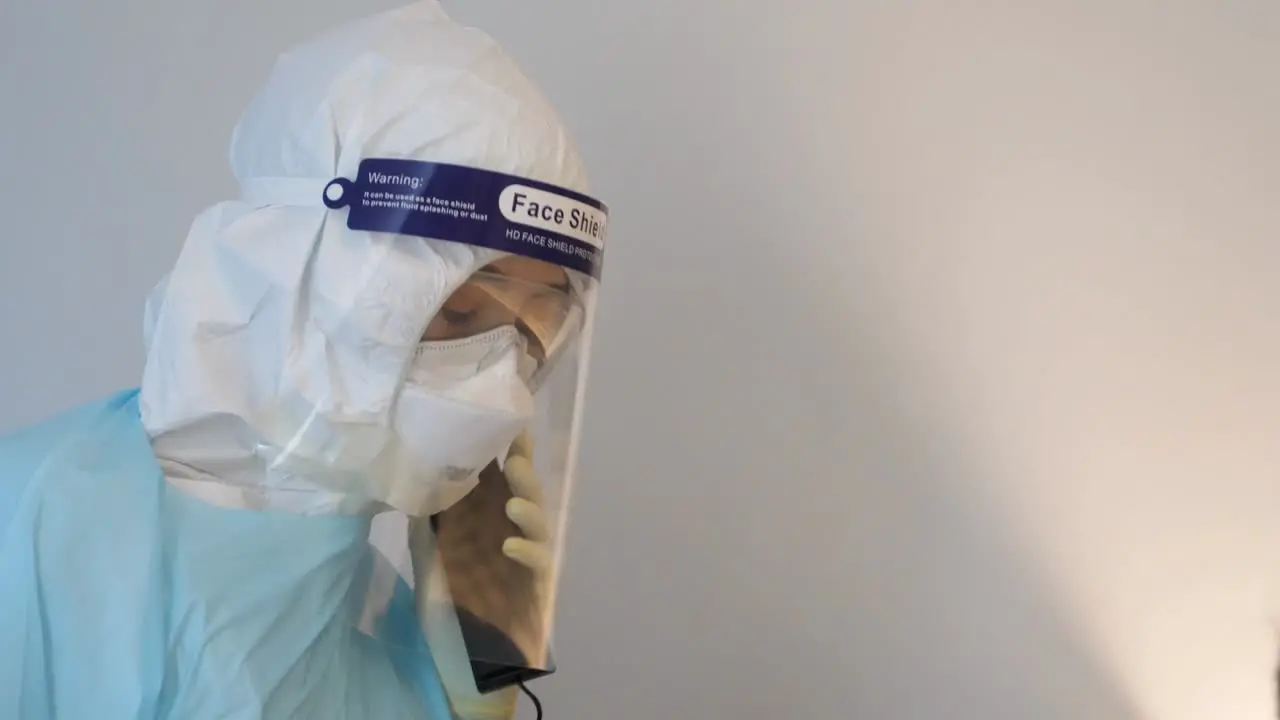 Medical Staff Wear PPE and Face Shield Answer The Phone Close Up