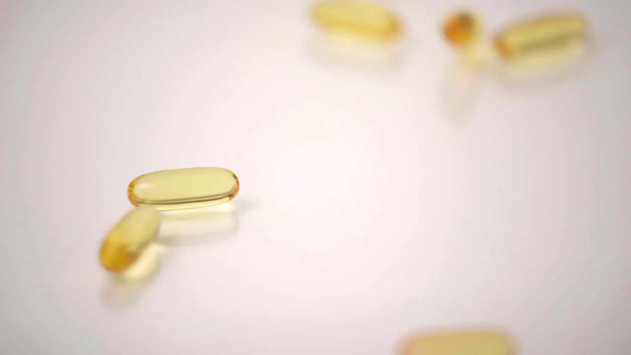 Macro of Yellow Pills Dropped onto White Background