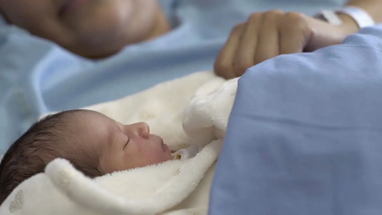 Newborn Baby Sleeping in Mom's Arms