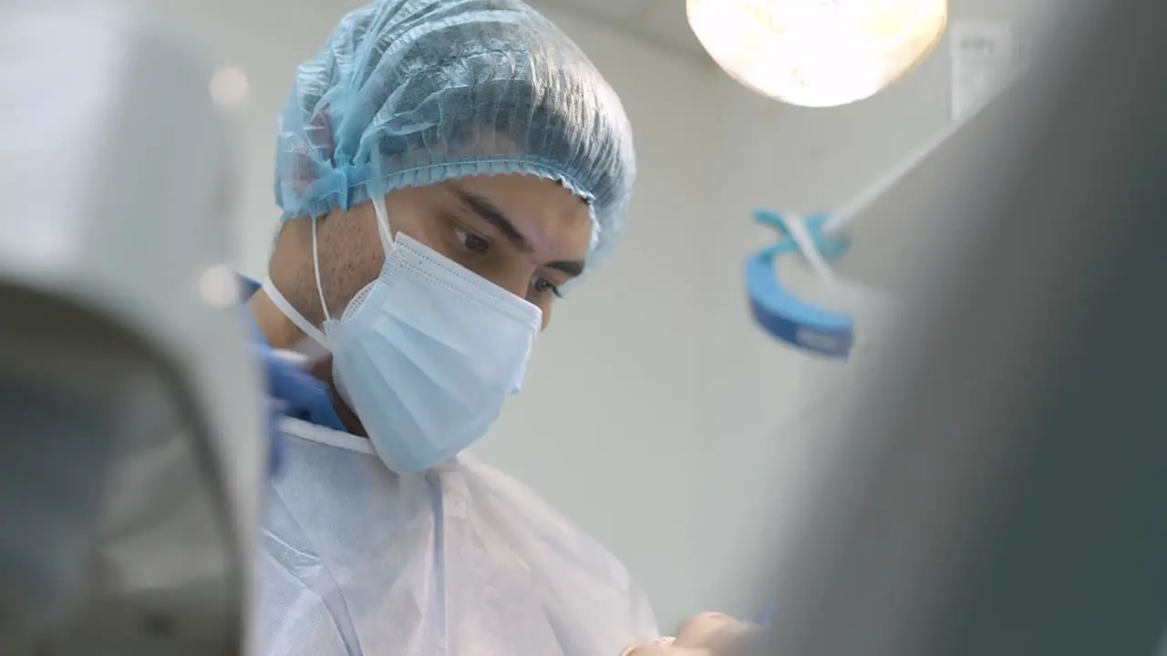 Man dentist sitting back examining teeth of patient in clinic hospital cabinet