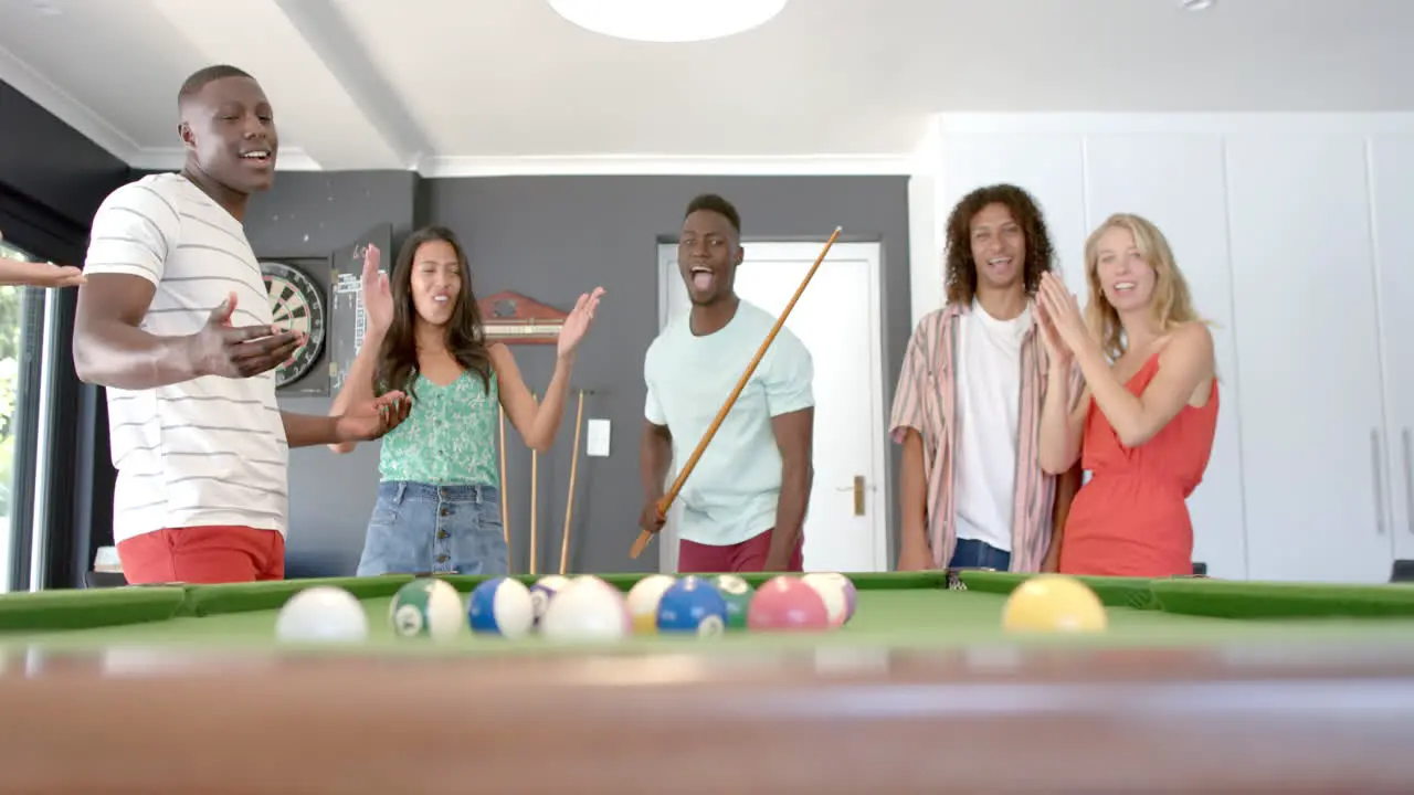 Diverse group of friends enjoy a game of pool at home