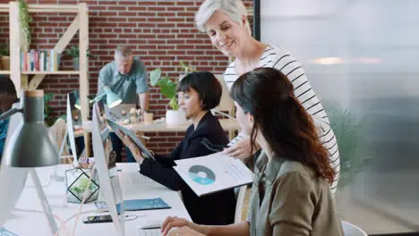 Manager helping woman at computer with documents