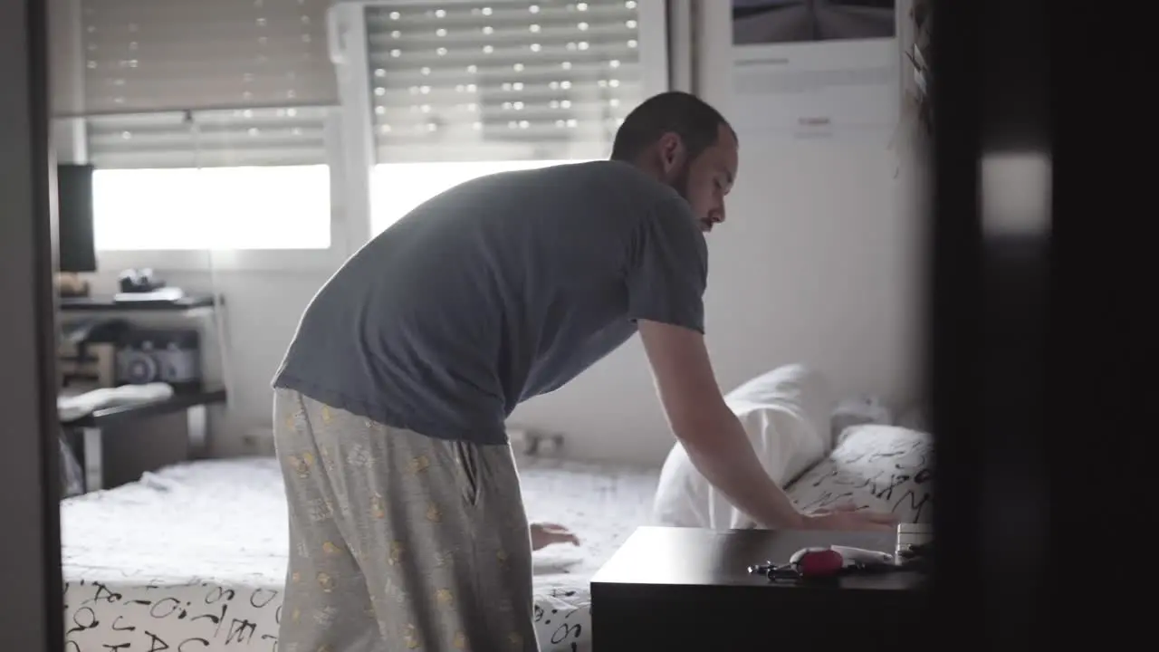 Man making the bed in the morning before starting the day