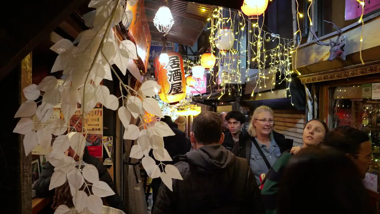 Foreign tourists exploring narrow nightlife alley in Tokyo at night