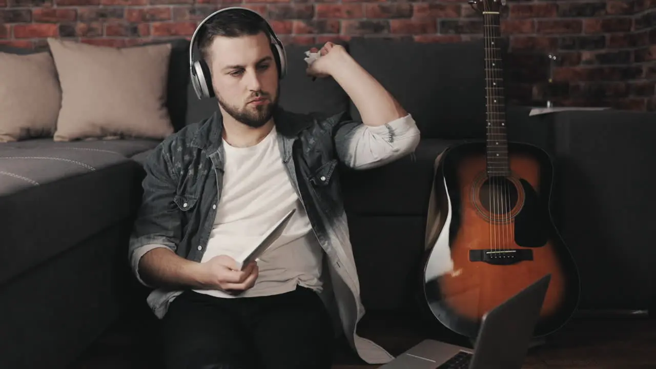 Young Musician Man Listening To Music With Laptop And Wireless Headphones Taking Notes At Home 1