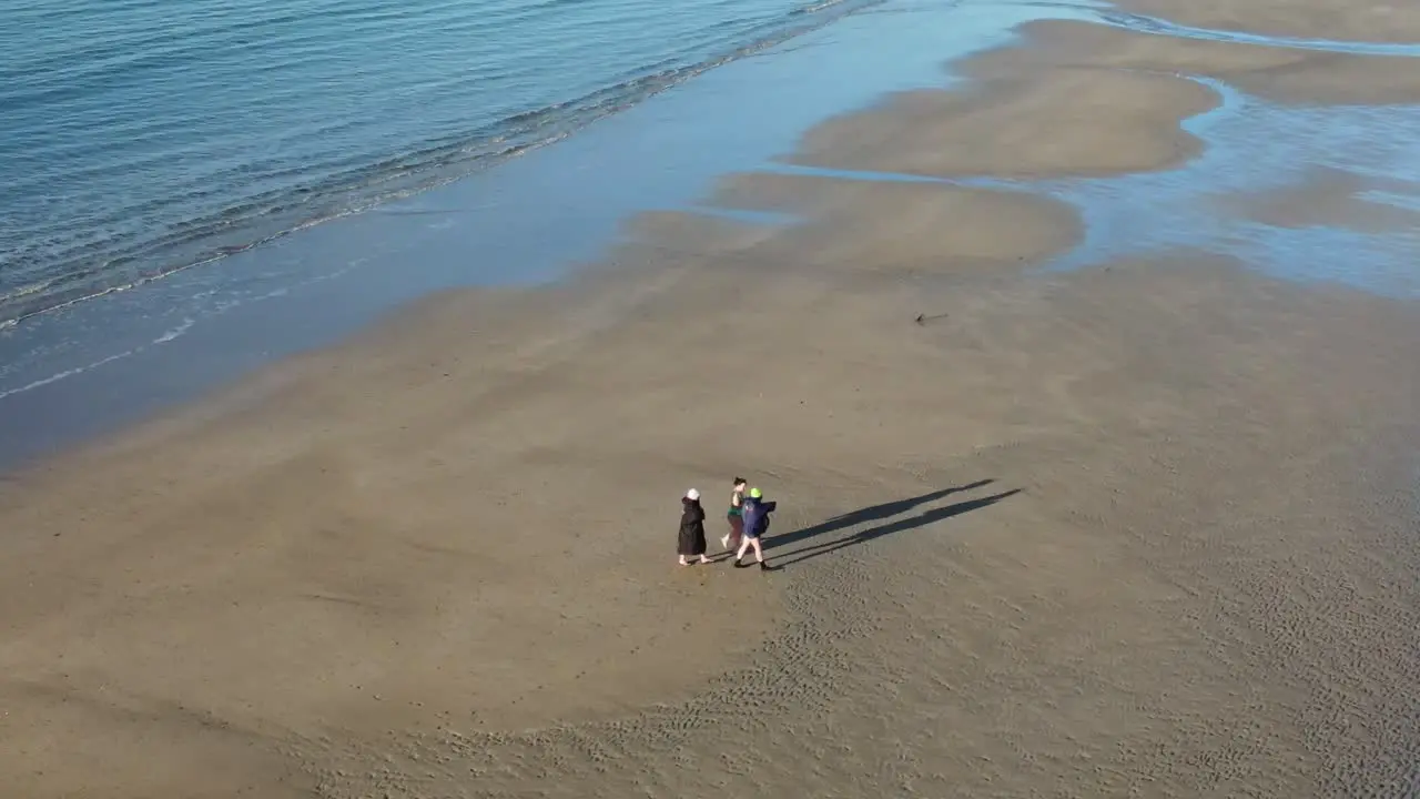 An aerial view over winter swimmers on a sandy beach