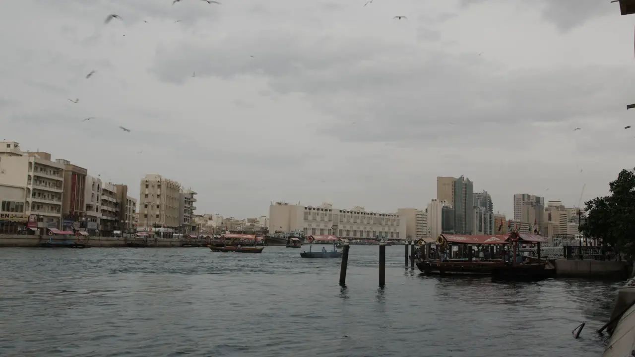 The river in Old Dubai in the UAE with middle easter boats and seagulls flying overhead on a cloudy and overcast day