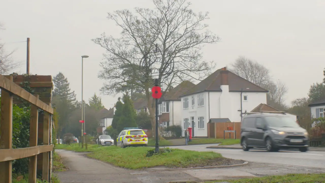 ZOOM OUT Middle class English suburb with a police car on patrol and a senior citizen with a shopping bag