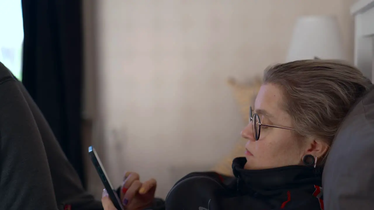 A woman lies in her bed scrolling through social media on her phone