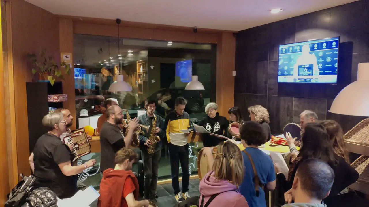 Group of musicians with men and women playing instruments and singing live in a bar entertaining customers during the evening celebration shooting turning right Ordes Galicia Spain