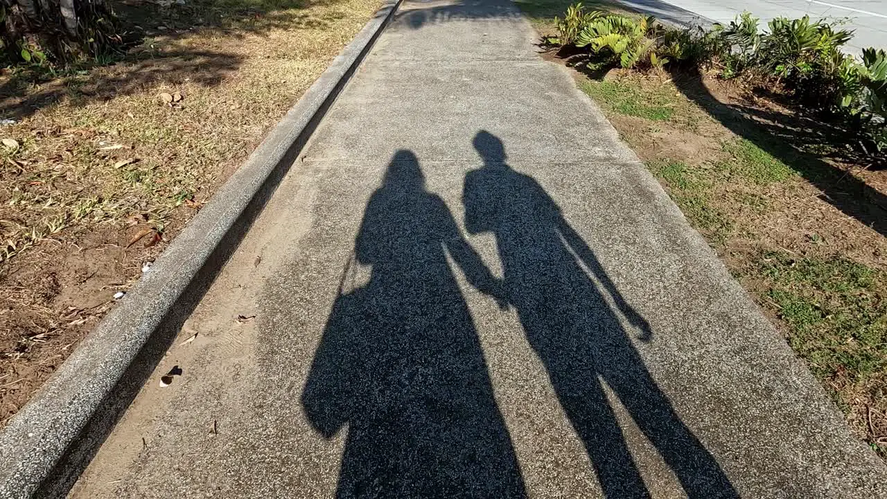 shadow of an engaged couple walking on the sidewalk on a sunny day the woman asking to hold hands in a sign of love unhealthy relationship concept