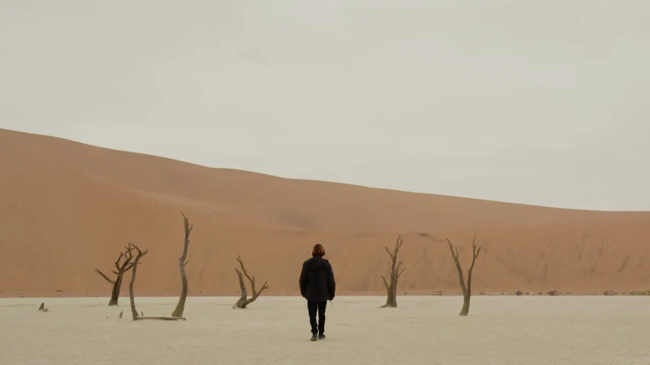 A white person walks through a desert