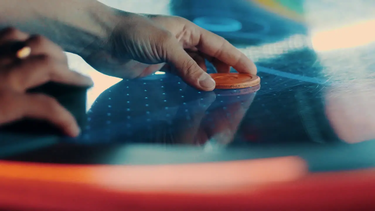 Starting a game of air hockey by placing the puck on the table in slow motion