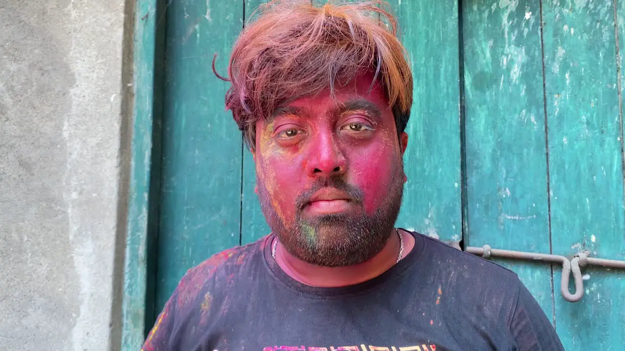 A static shot of a boy removing mask from his face after playing Holi in front of camera