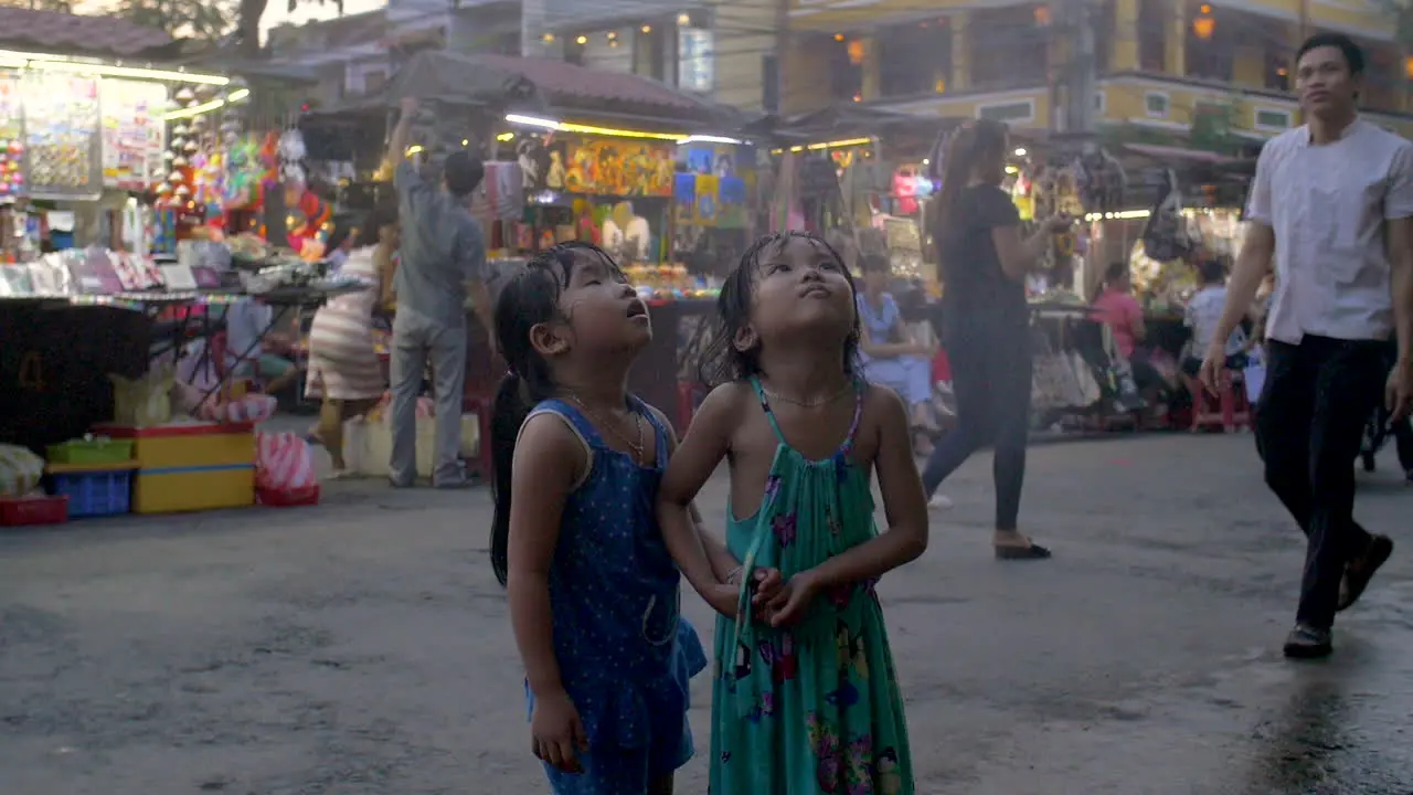 Young asian girls stand under sprinkler and smile On the street in Vietnam