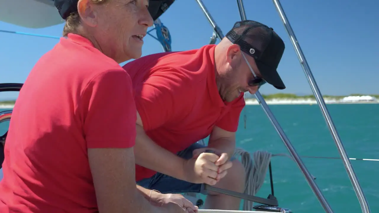 Man spinning the handle to get the rope back on a sail boat