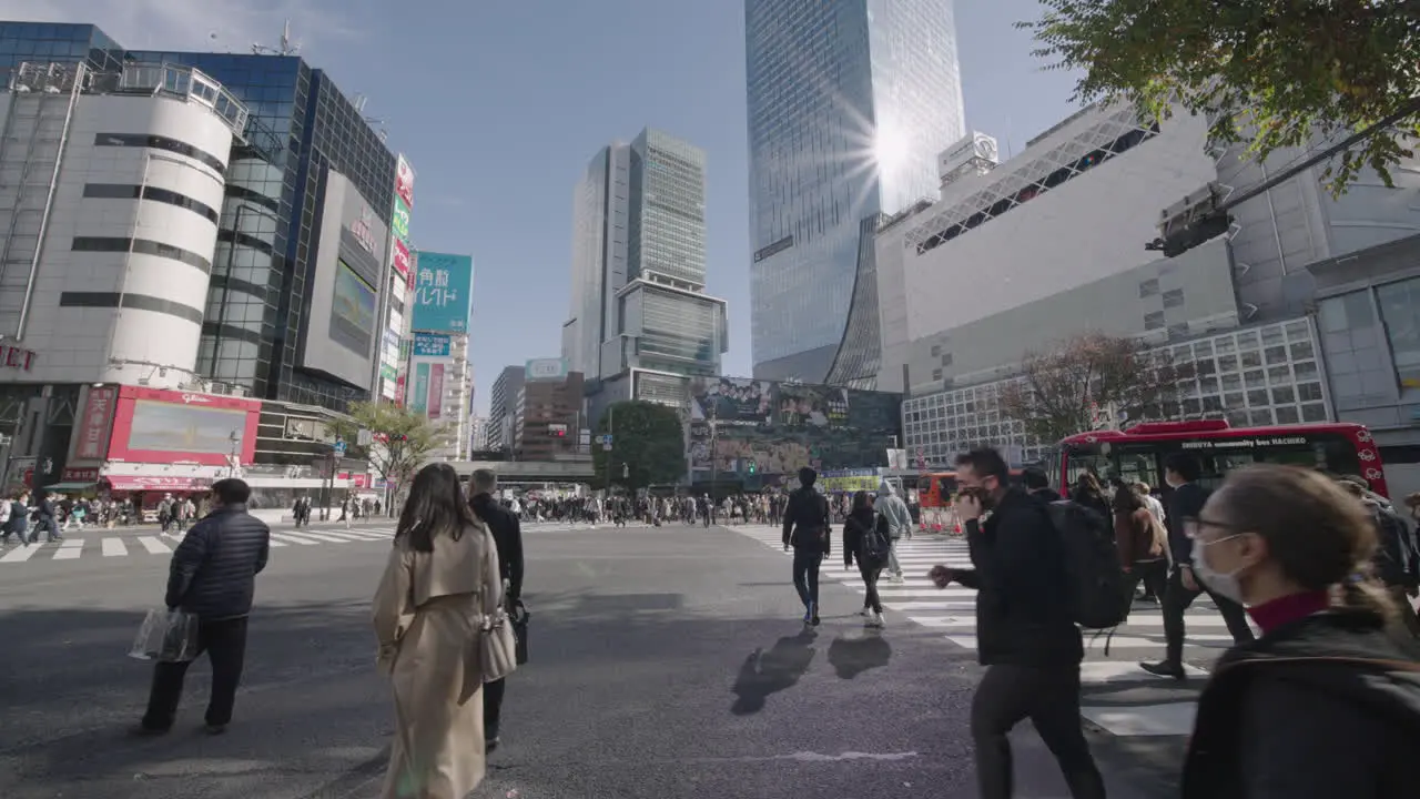 People Walking On Famous Intersection Of Shibuya Crossing With Sunbeam Against Building In Tokyo Japan