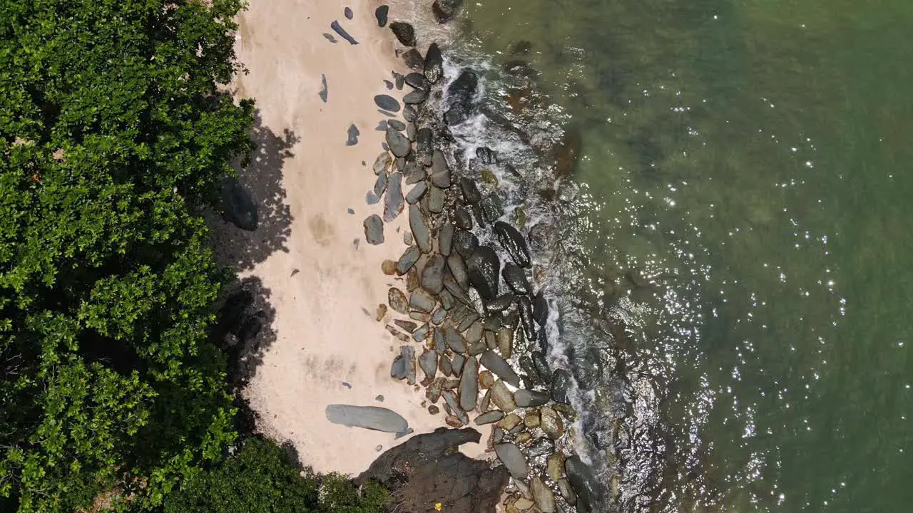 Aerial downward pan shot of beach jungle and rocky coastline