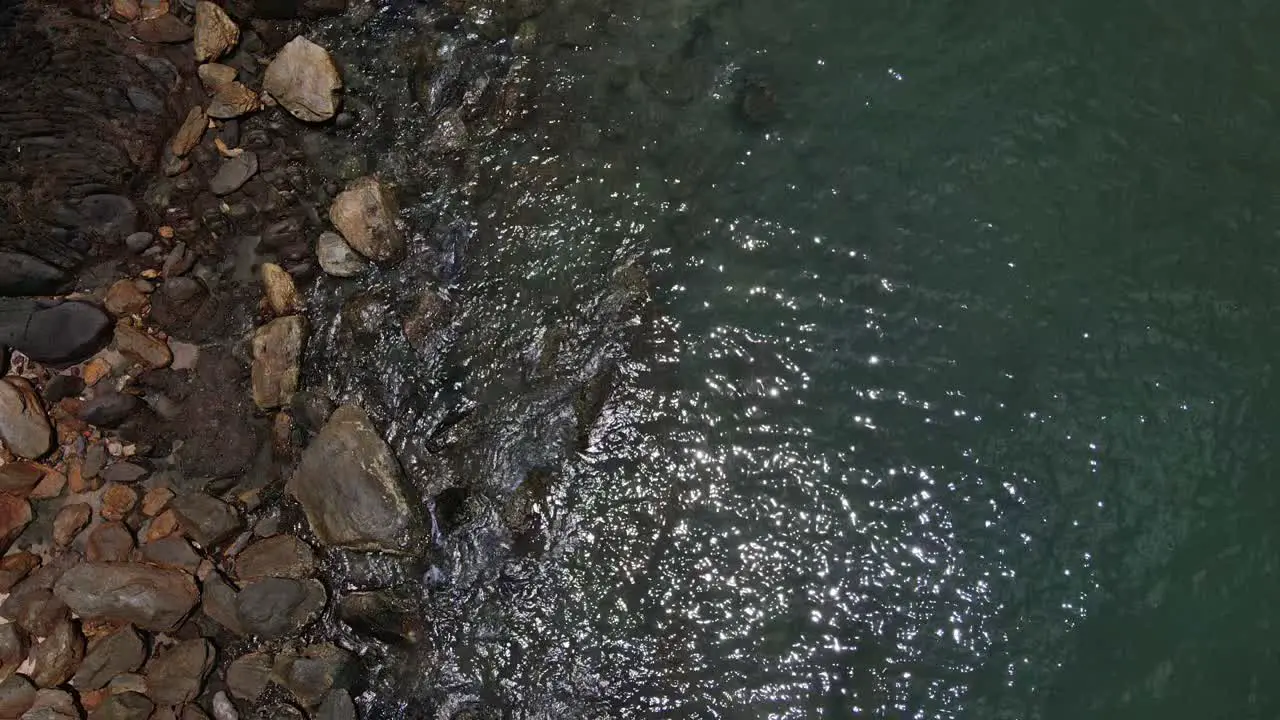 Drone vertical tracking shot of Ocean meets rocks on a tropical Island