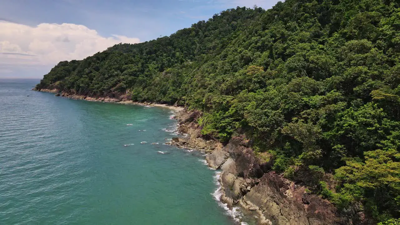 Drone dolly shot of jungle coastline with small beach and ocean