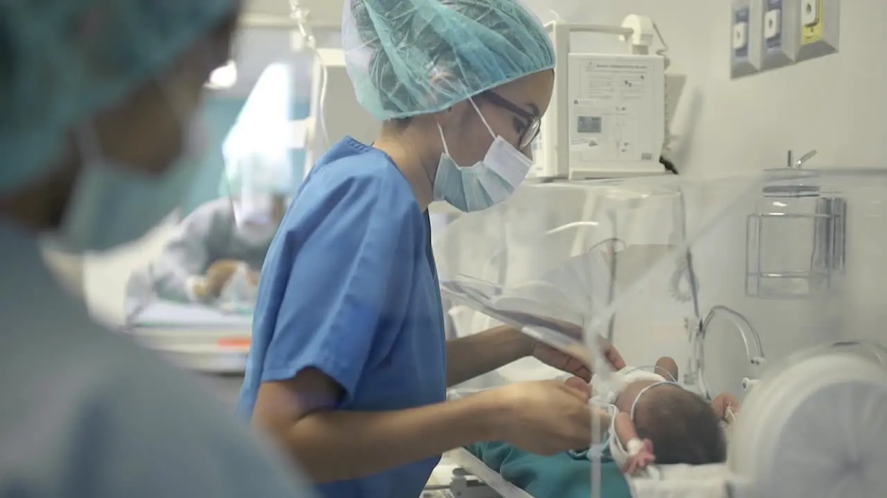 Doctor Treating Newborn Baby in Incubator