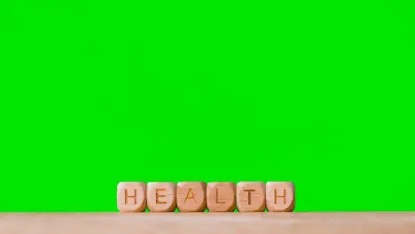 Medical Concept With Wooden Letter Cubes Or Dice Spelling Health Against Green Screen Background