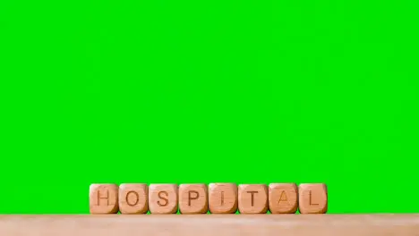 Medical Concept With Wooden Letter Cubes Or Dice Spelling Hospital Against Green Screen Background