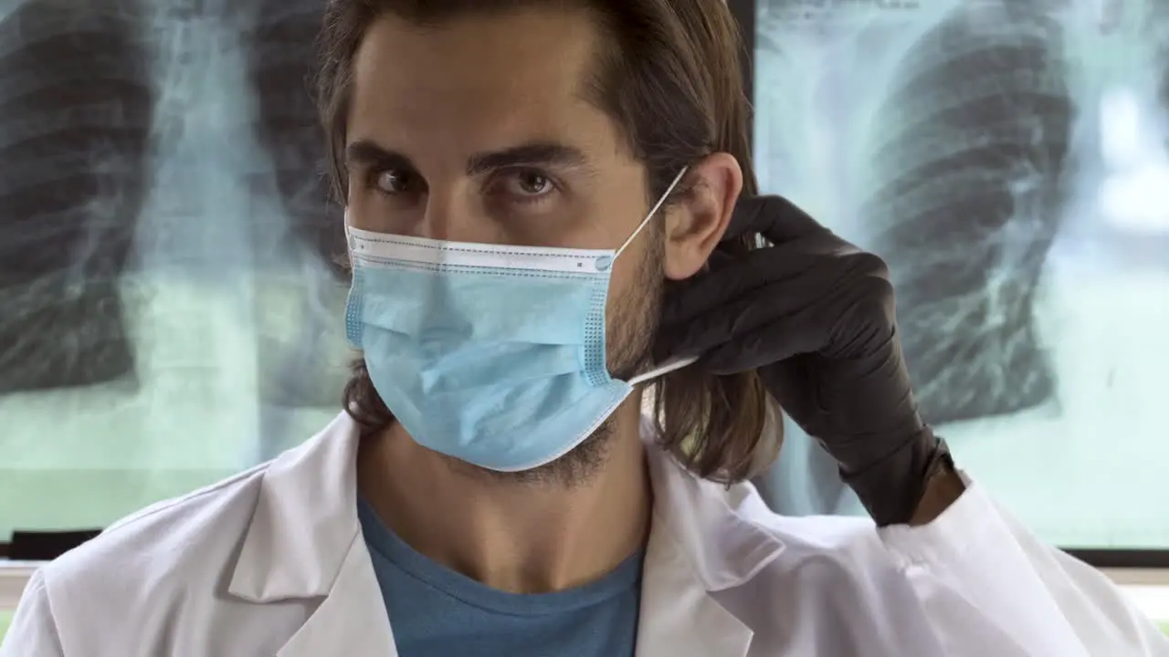 Doctor staring sharply while putting on mask protective goggles