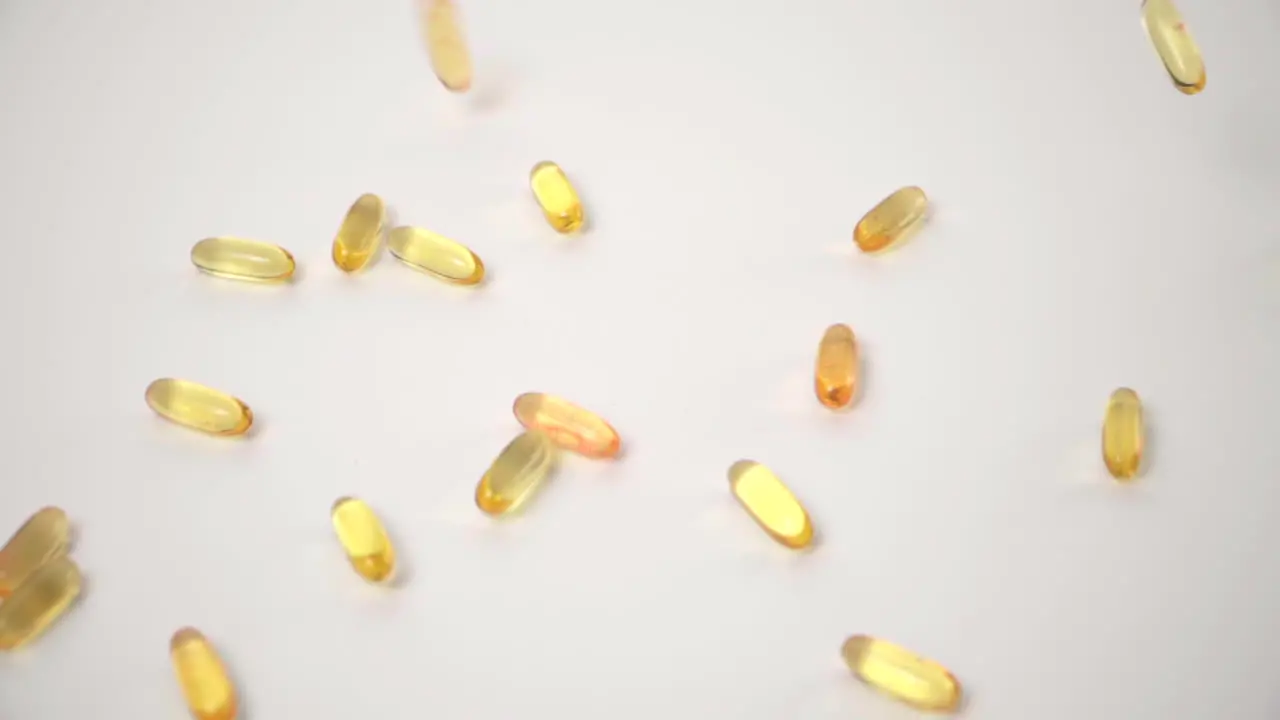 Slow Motion of Yellow Pills Dropped onto White Background