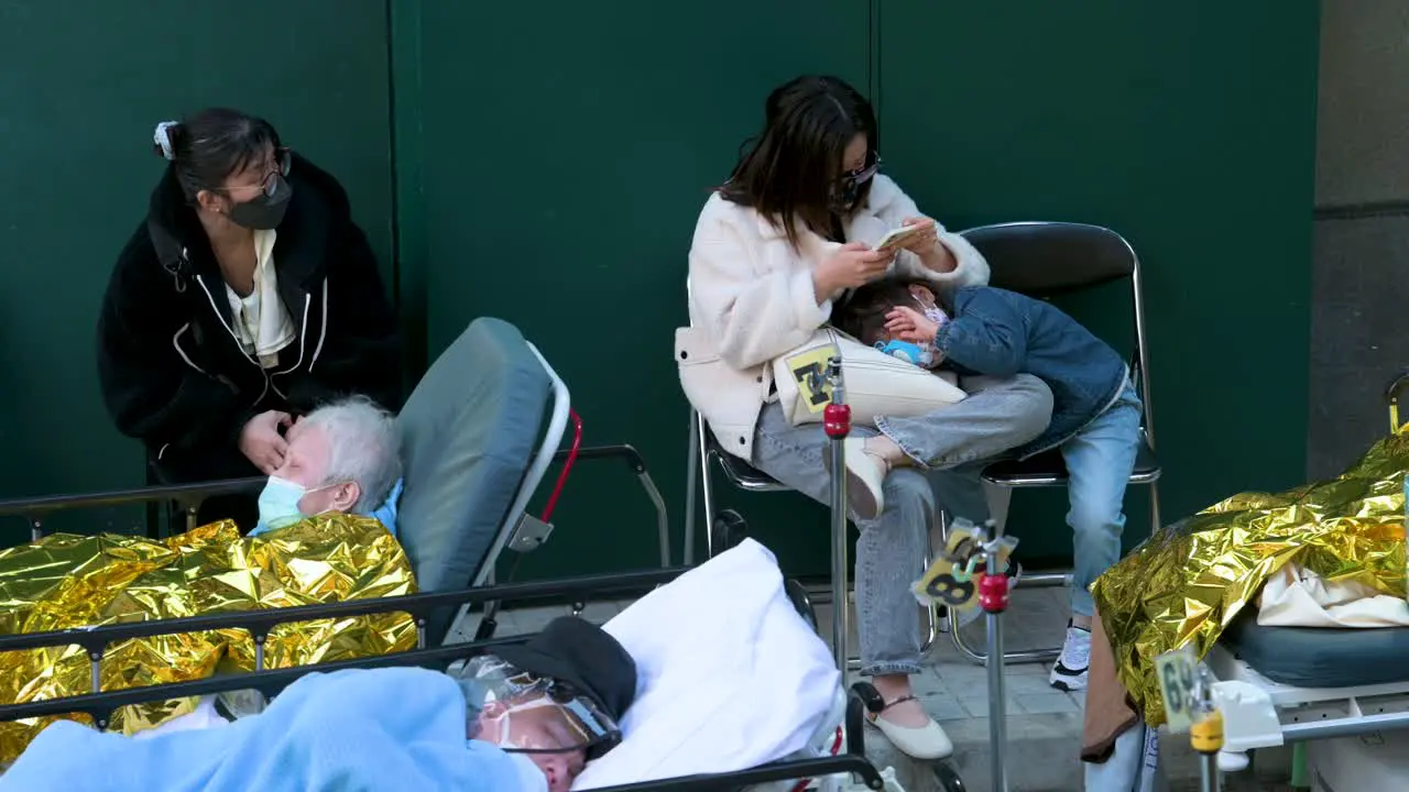 A mother and her child wait to be treated after showing Covid-19 symptoms as ill patients rest and lie in beds outside an overcrowded hospital while the medical system collapses with hospitalizations