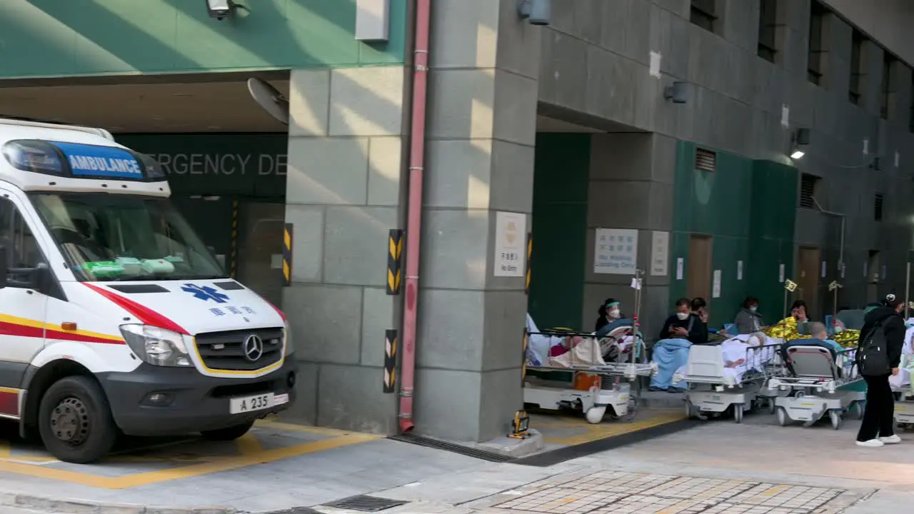 A panning shot shows an ambulance stationed at the hospital entrance as patients with Covid-19 symptoms lie in the bed outside an overcrowded hospital while the medical system collapses