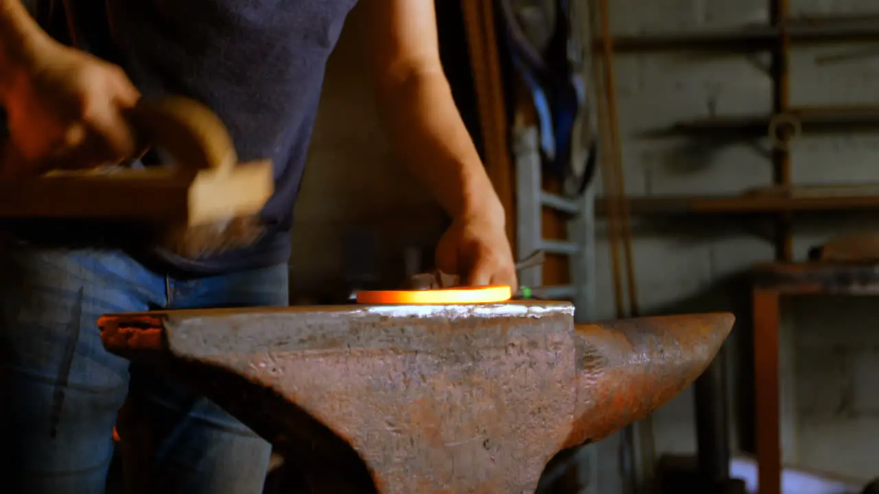 Metalsmith brushing horseshoe in fire 4k