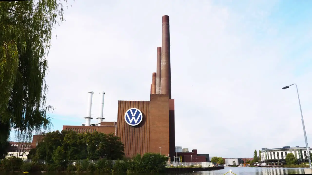 View Looking At VW Logo On Side Of Volkswagen factory Building With Chimney Towers At Wolfsburg Germany