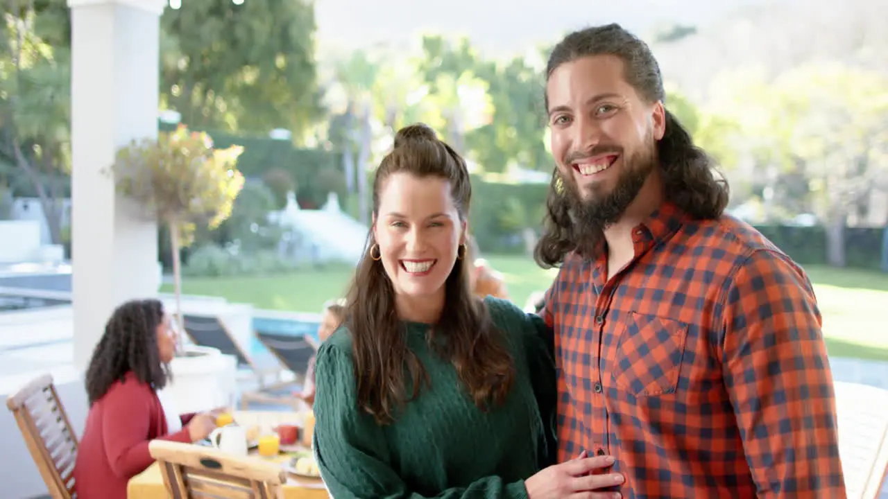 Two happy caucasian male and female friends posing during celebration meal in sunny garden