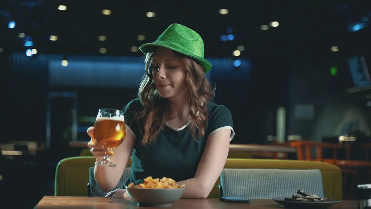 Pretty Young Woman Drinking Beer And Wearing An Irish Green Hat